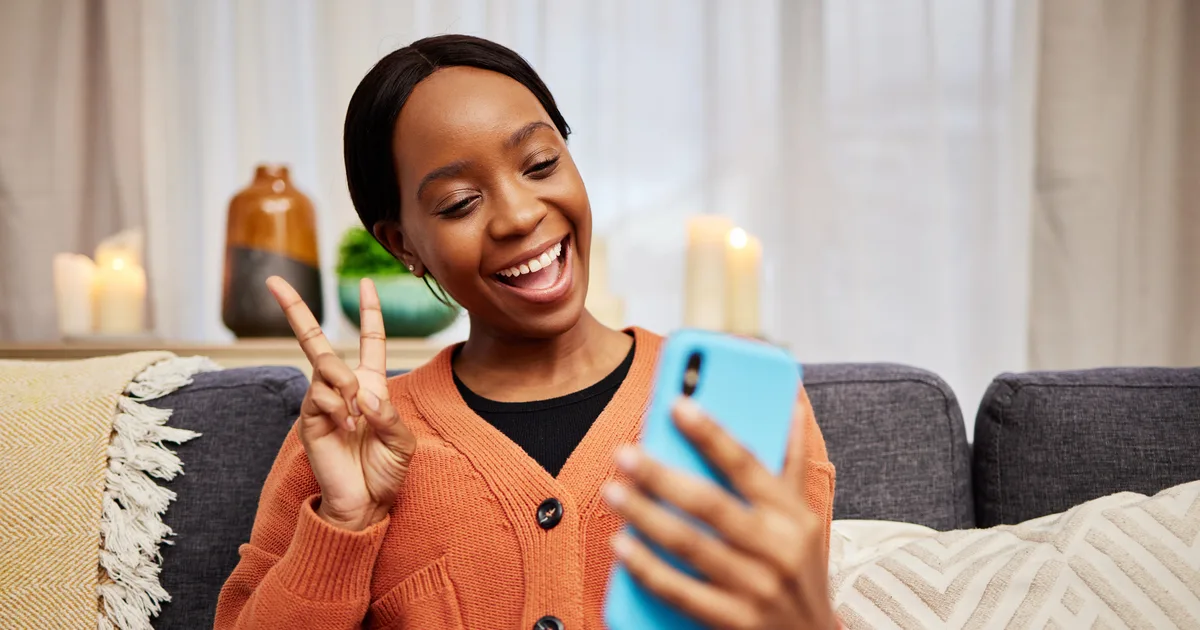 Une créatrice fait un signe de paix devant son téléphone