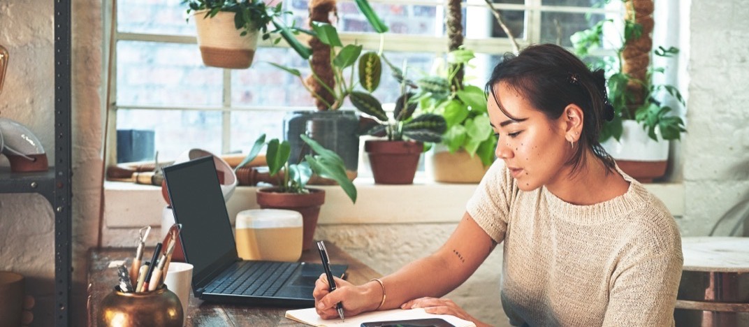 Une créatrice prend des notes à son bureau